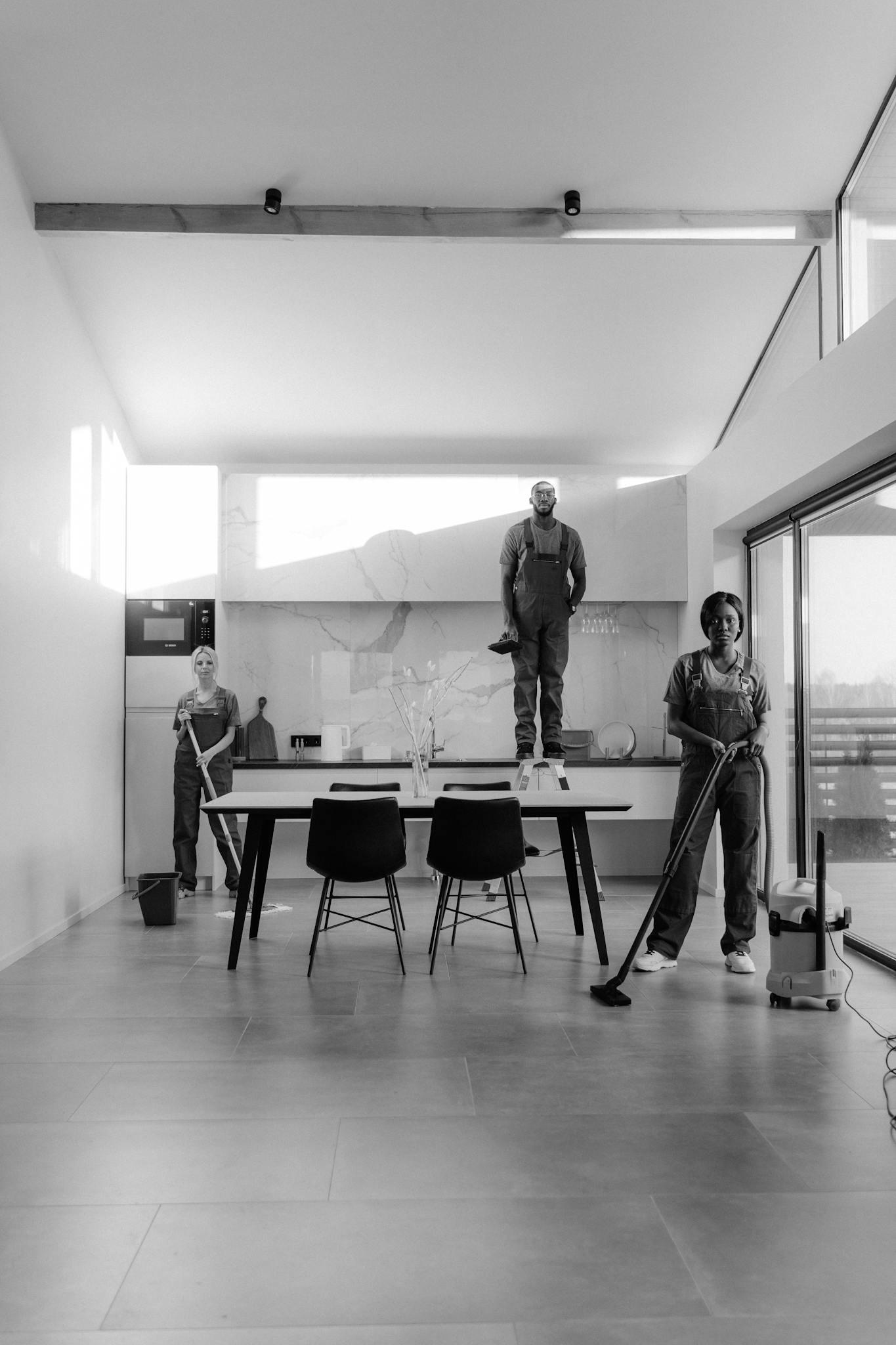 Black and white photo of a cleaning crew in a modern home, showcasing teamwork.